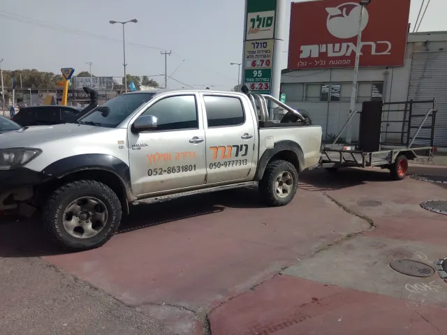 טנדר ניר גרר עם עגלת גרירה ריקה בתחנת דלק